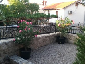 Stroll along the gravel pathway to a serene outdoor space surrounded by lush greenery and a charming stone wall.
