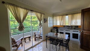 A kitchen with a dining area, a stove, and a window with curtains. - Hotel Quinto Nivel RD (Salcedo)