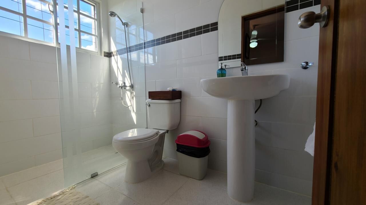 A bathroom with a toilet, a shower, and a sink.
