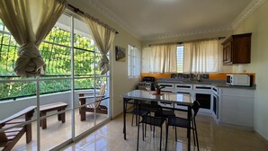 A kitchen with a dining table and chairs, a stove, and a microwave. - Hotel Quinto Nivel RD (Salcedo)