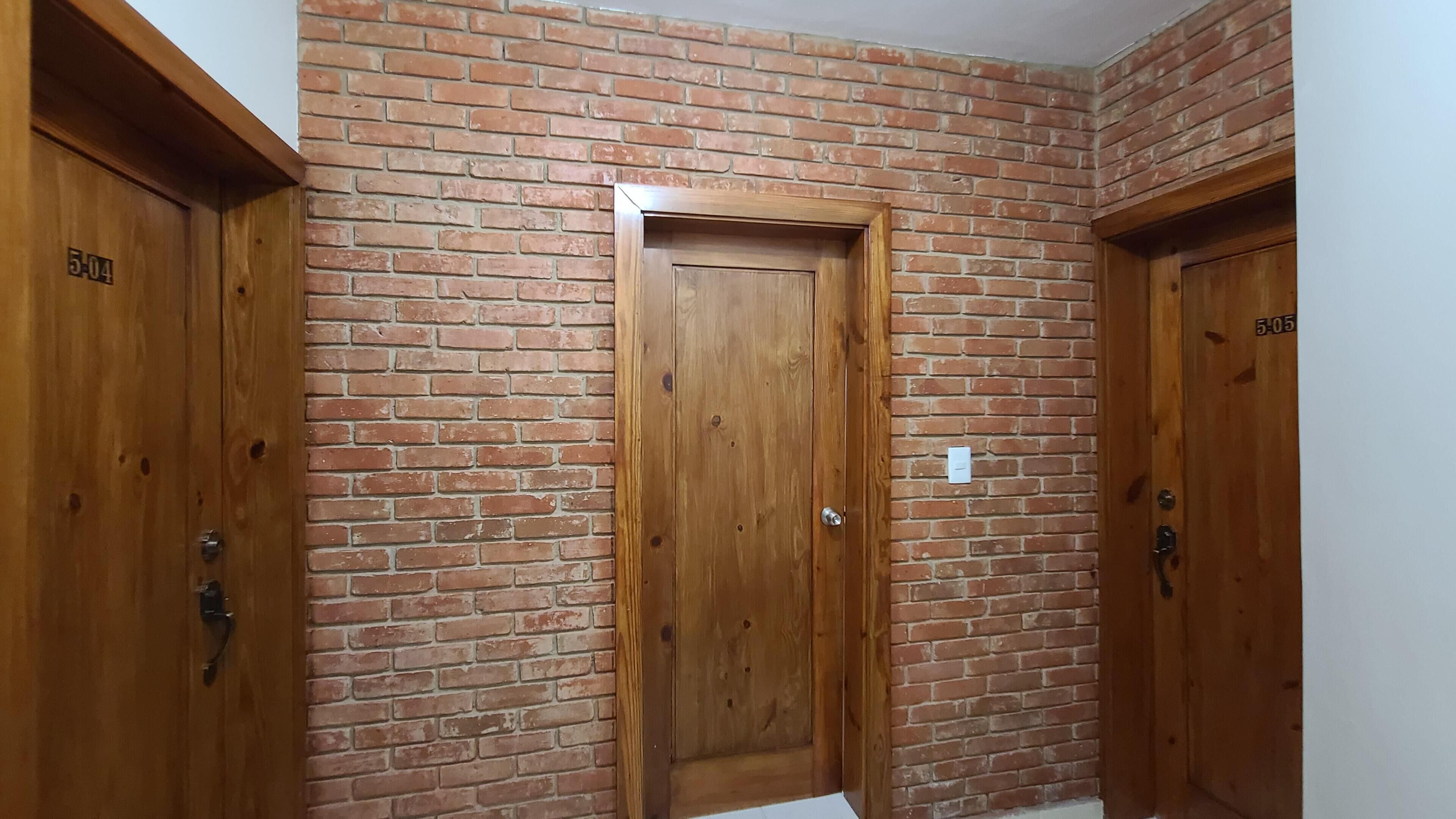 Un pasillo con paredes de ladrillo y puertas de madera, cada una numerada.