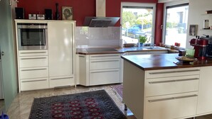 A modern kitchen with white cabinets, a built-in oven, a coffee maker, and a large window offering a view of the street.