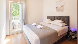 Een slaapkamer met een bed, nachtkastje, foto aan de muur en uitzicht op het natuurlijke landschap.