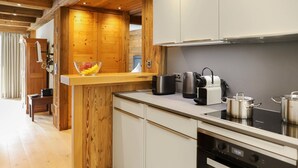 A modern kitchen with wooden accents, stainless steel appliances, and a breakfast bar. - Dianthus by Interhome (Zermatt)
