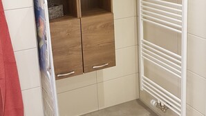 A bathroom with a wooden cabinet, a white towel rack, and a tiled floor.