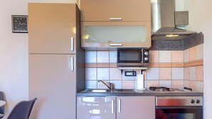 Een kleine keuken met een magnetron, fornuis en spoelbak.