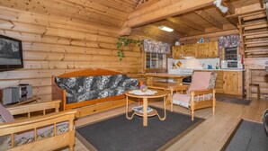 Et hyggeligt sommerrushus indeni med træpaneler, en sofa, et spisebord og et køkken.