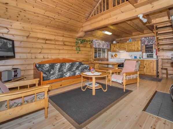 A cozy cabin interior with a sofa, chairs, a small table, a kitchen area, and wooden walls. - Kissaniemi by Interhome (Iisalmi)