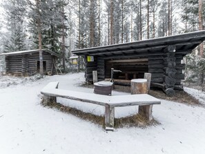 A wooden cabin with a bench in front, surrounded by snow-covered trees. - Kissaniemi by Interhome (Iisalmi)