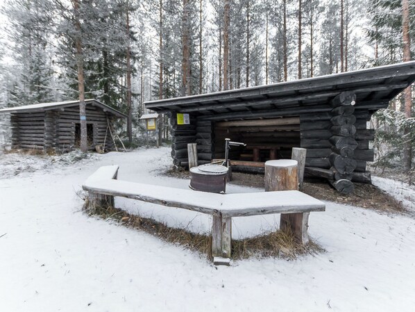 A wooden cabin with a bench in front, surrounded by snow-covered trees.