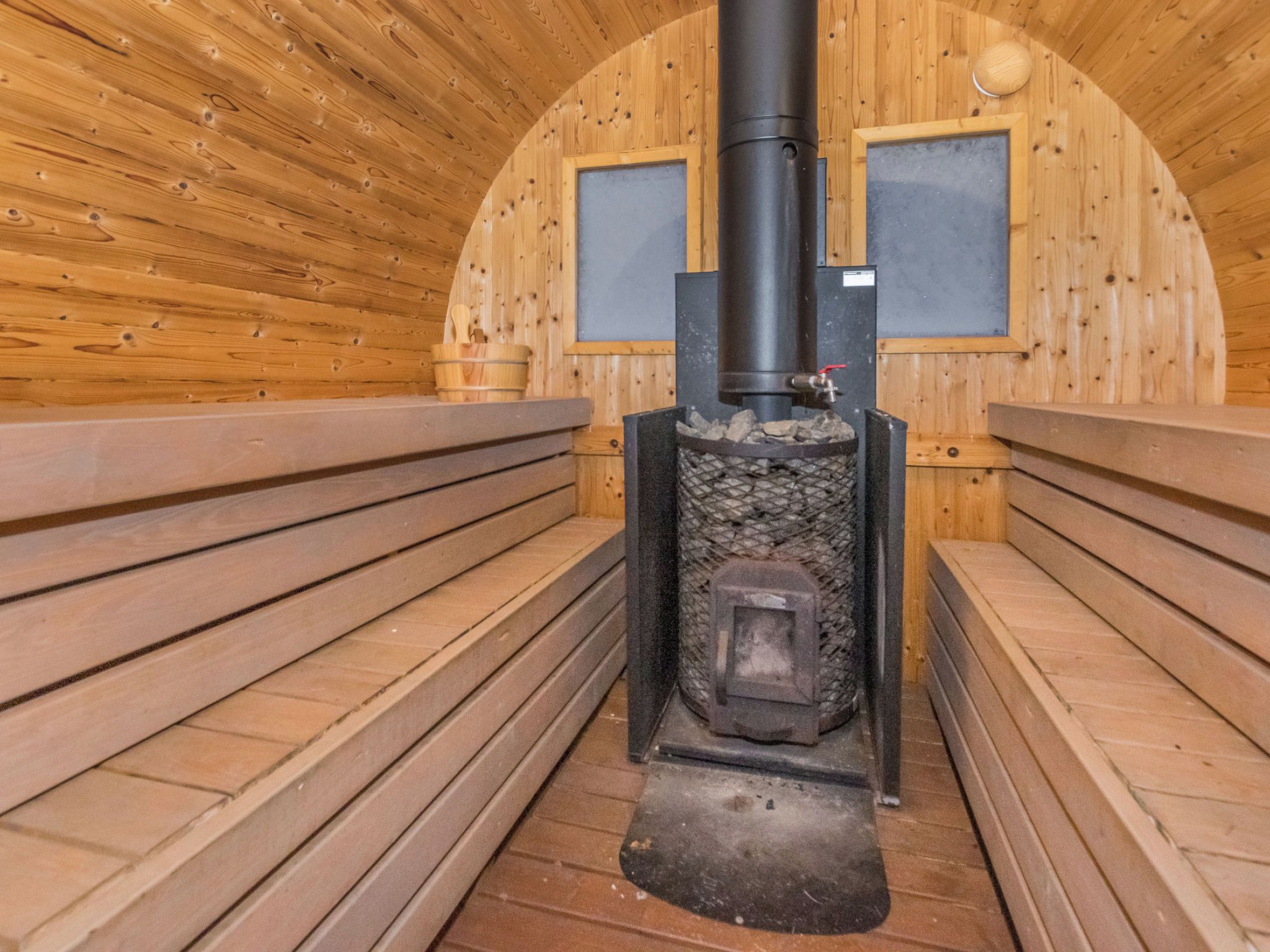 A sauna with wooden benches and a central stone heating unit.