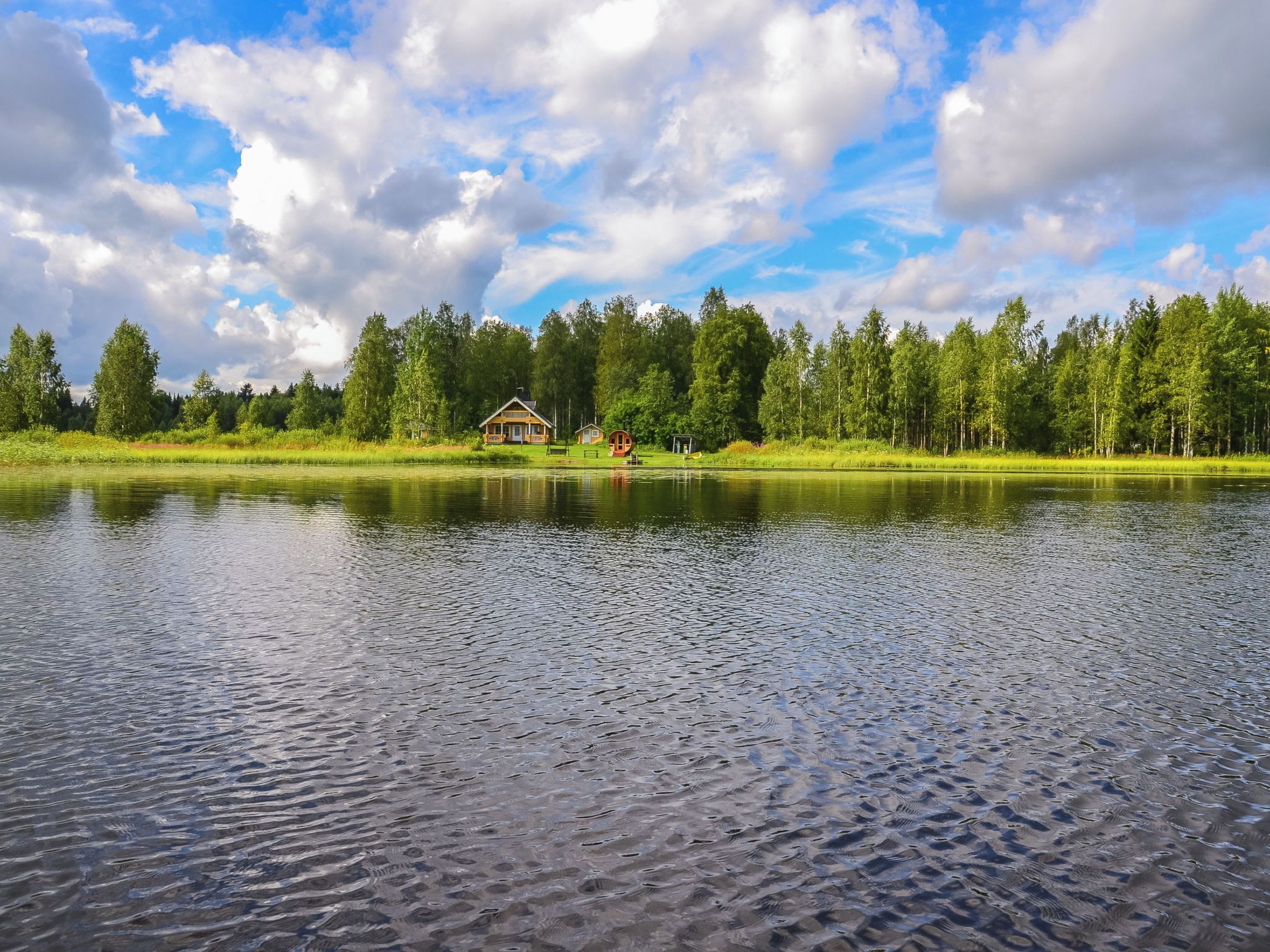 Ein See mit einer Holzhütte und einem kleinen Gebäude am Ufer.