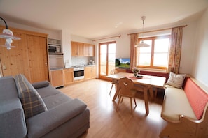 Un espacio habitable funcional con sofá, mesa de comedor, sillas, televisor y zona de cocina.