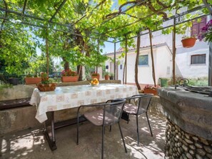 An outdoor patio with a table and chairs, surrounded by potted plants and a stone wall. - Apartment Judita by Interhome (Crikvenica/Jadranovo)