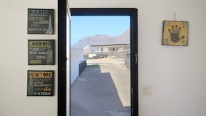 Un couloir donnant sur les montagnes, avec une porte et des panneaux indicateurs fixés au mur, indiquant les directions de Paris, Londres et New York.