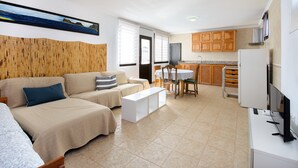 Un salon comprenant un canapé, une table basse, un téléviseur et un coin repas avec une table et des chaises.
