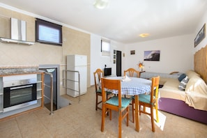 Una cocina compacta con horno integrado, refrigerador y comedor con mesa y sillas.
