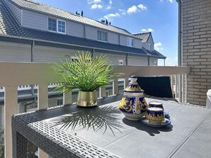 A balcony with a potted plant, two ceramic tea pots, and a table. - The Horseshoe with parking by Interhome (Bredene)