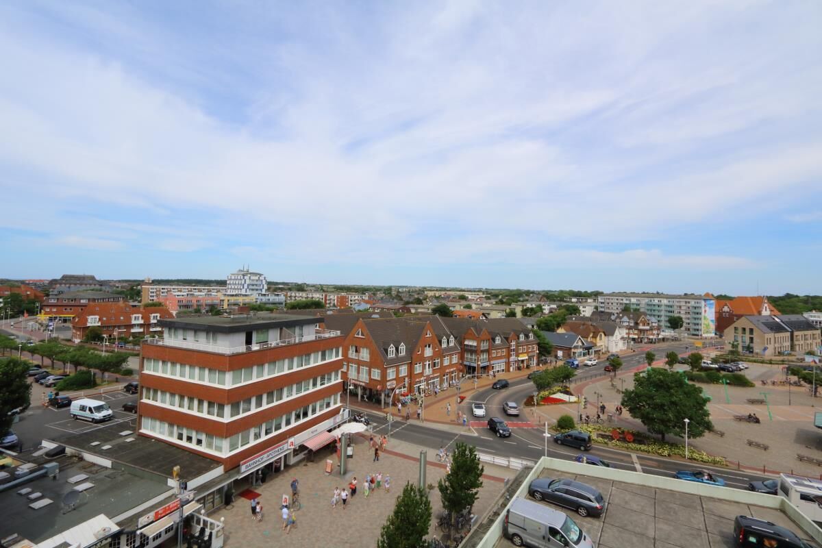 A town square with buildings, a roundabout, and a parking area.