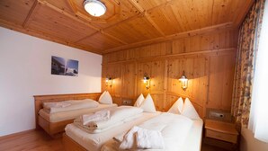 A wooden-paneled room with three beds, wall-mounted lights, and a picture on the wall.