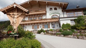 A traditional wooden building with a balcony, a wooden crucifix, and a sign reading 'BERGGASTHAUS Sochnöser.'