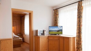 A room with a wooden cabinet, a television, and a bed.