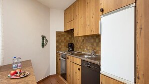 A compact kitchen with wooden cabinets, a dishwasher, and a white refrigerator. - Resort al Centro by Interhome (Breganzona)