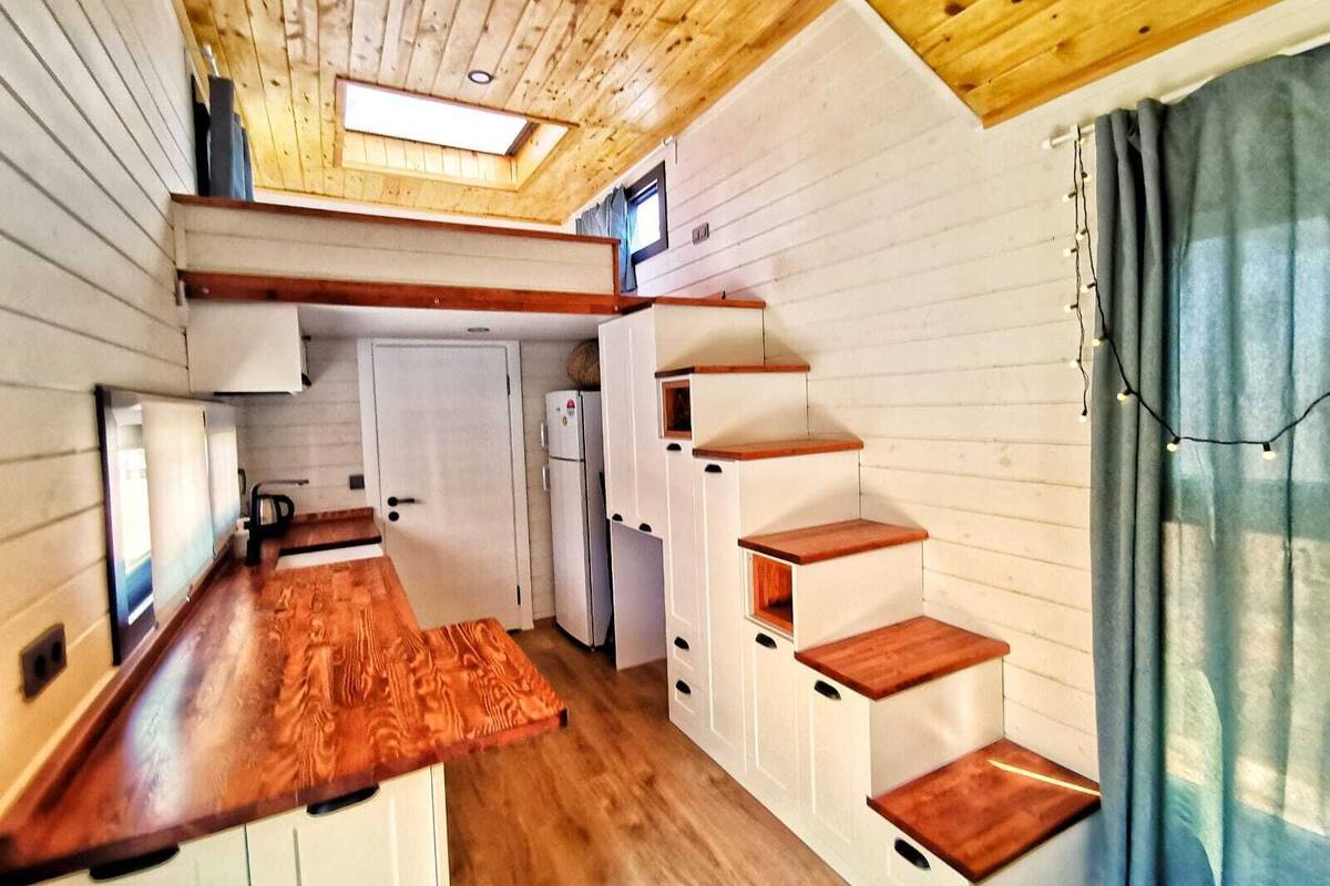 A compact kitchen with wooden countertops, a built-in stove, and a window above the sink.