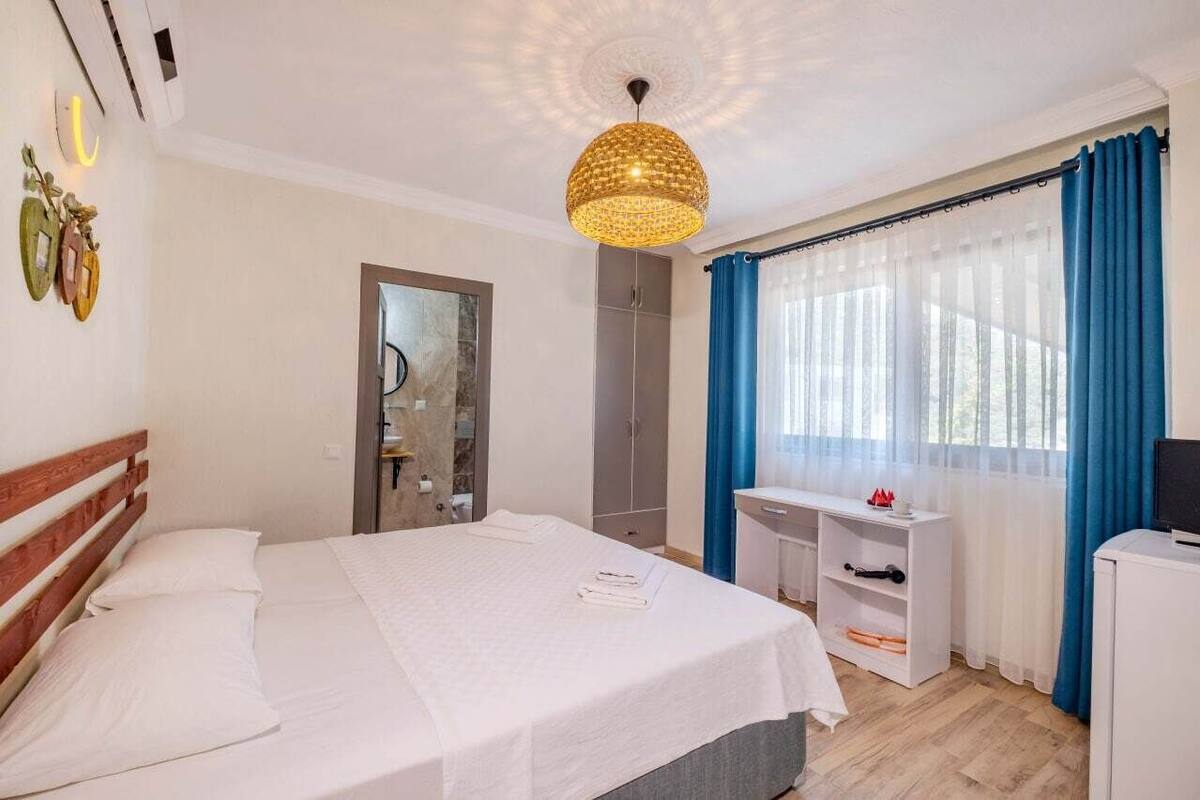 A hotel room with a bed, a desk, a wardrobe, and a TV.