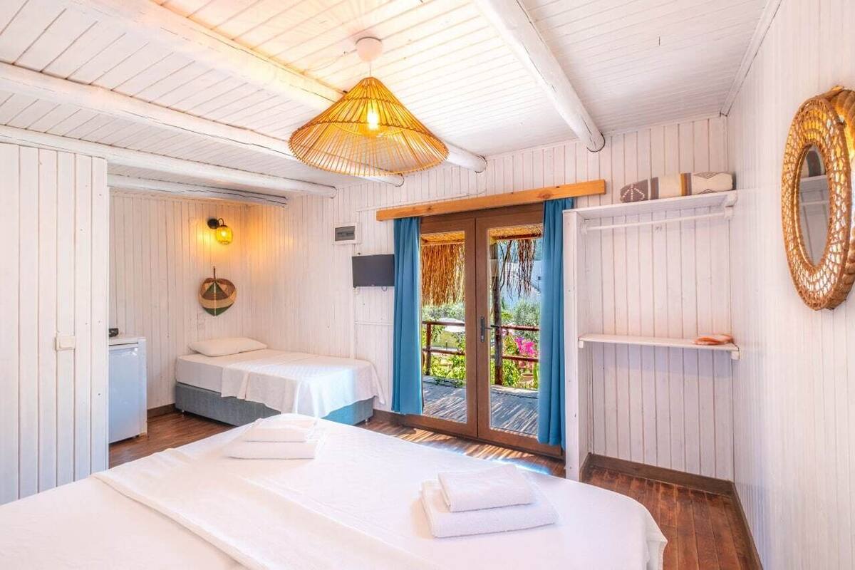 A room with two beds, a ceiling fan, a small TV, and a sliding glass door to an outdoor area.