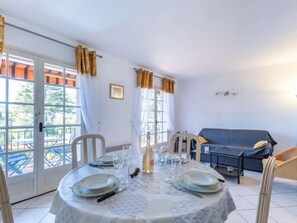 A dining area with a table set for four, a blue sofa, and a window with curtains.
