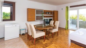 Una camera compatta con un tavolo da pranzo, quattro sedie, un angolo cottura con frigorifero e un letto.