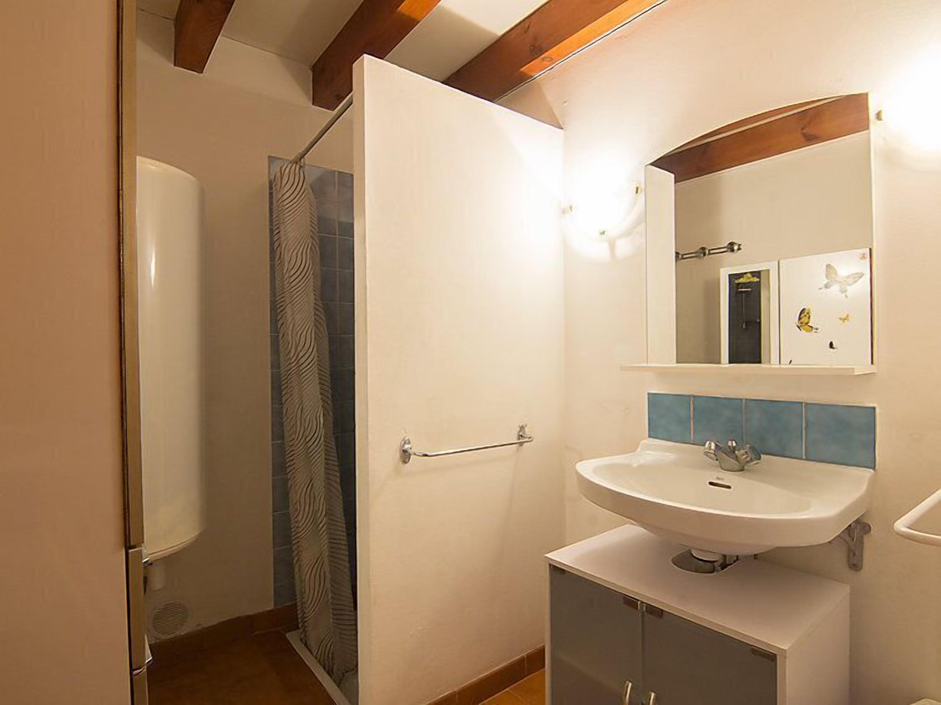 Bany amb dutxa, un lavabo i un mirall.