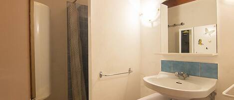 Bany amb dutxa, un lavabo i un mirall.
