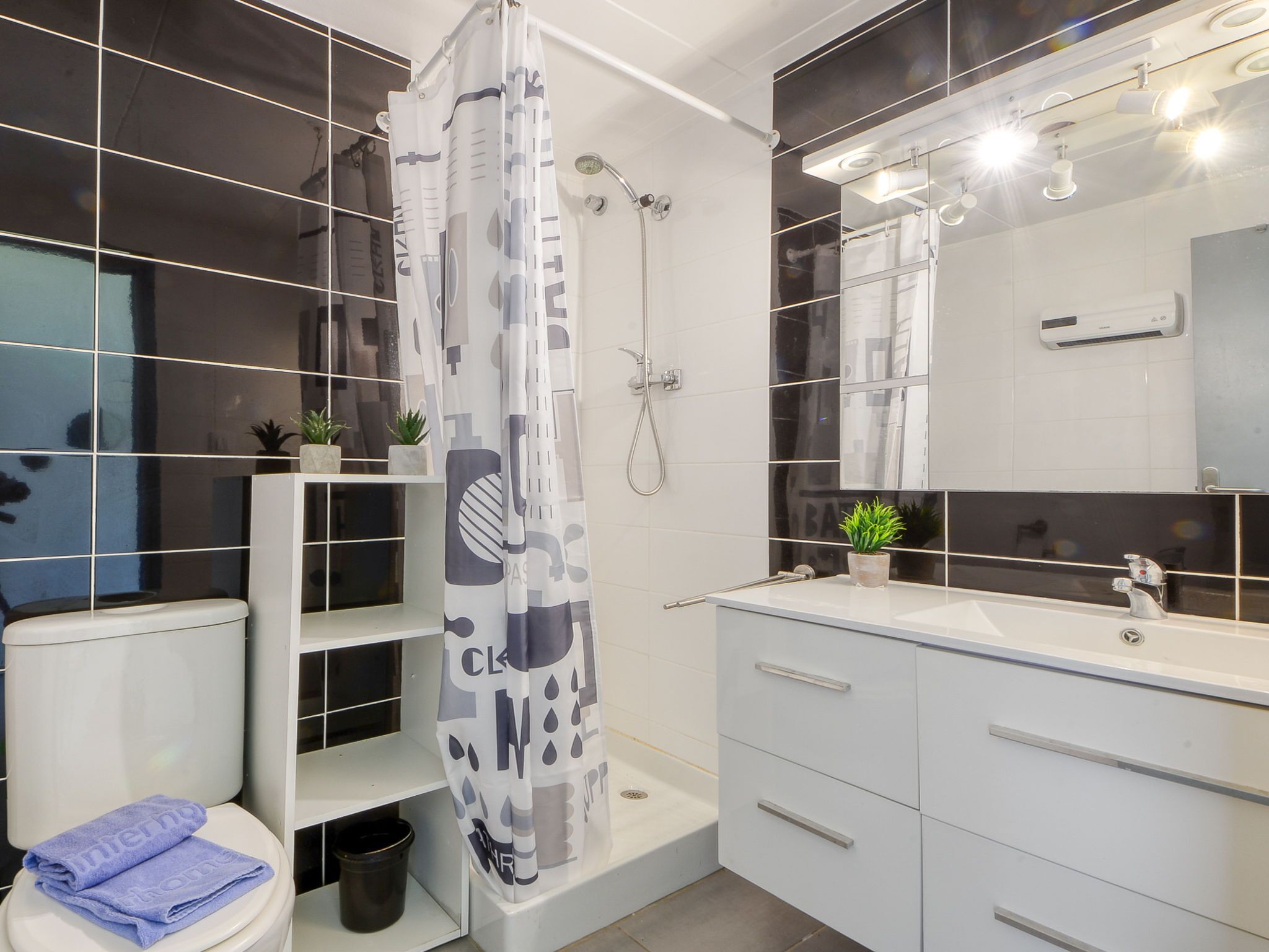 Une salle de bain moderne équipée d’une douche, de toilettes et d’un meuble-lavabo.