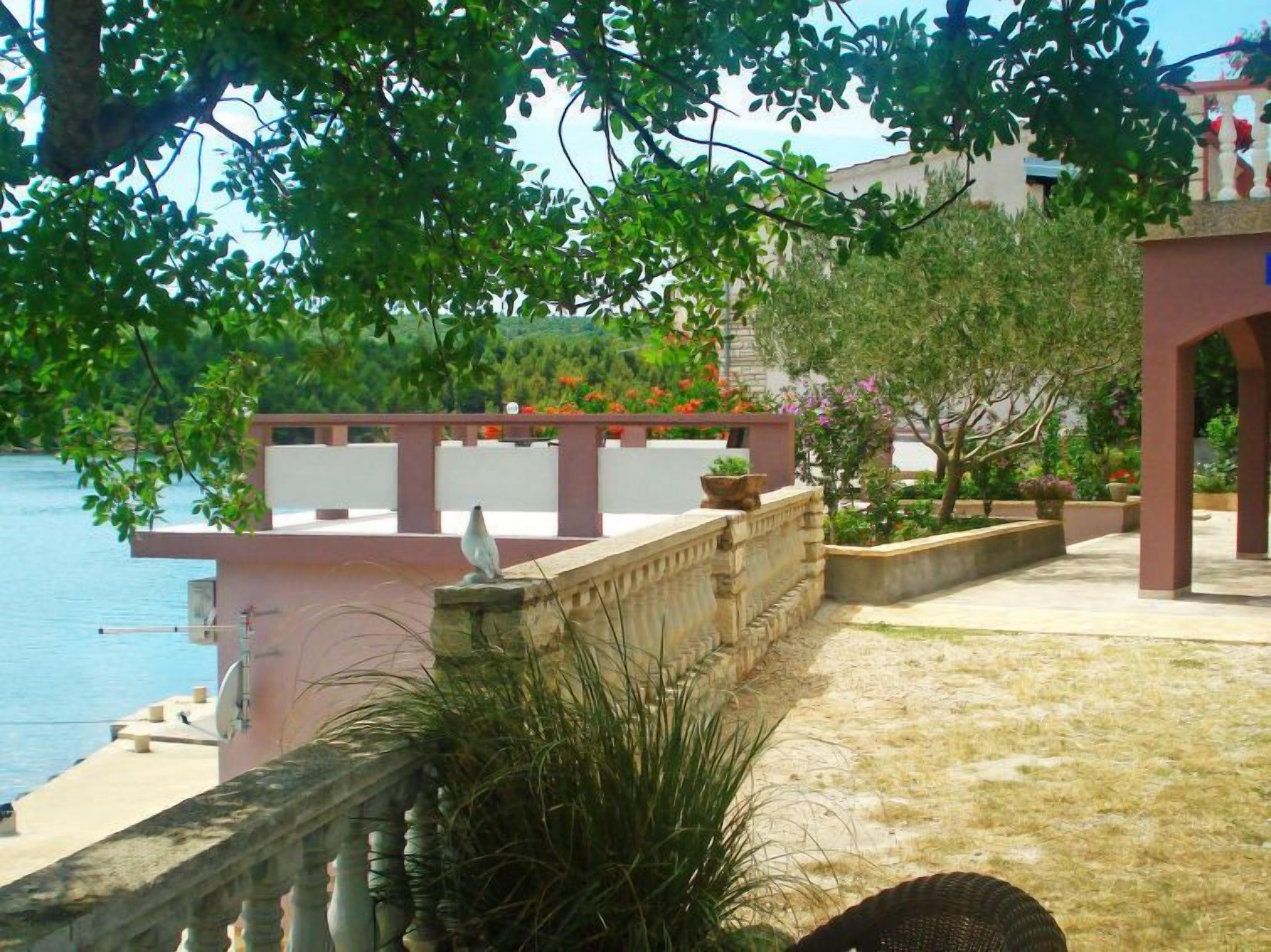 Una propiedad costera con un muro de piedra, una pérgola y vistas al mar.
