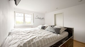 Een slaapkamer met een bed, een raam en een muursticker.
