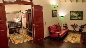 A cozy living room with a red sofa, wooden flooring, and a staircase leading to an upper floor. - Royal Bar & Hotel (Kandy)