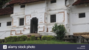 A white building with a red-tiled roof, featuring a central arched doorway and multiple windows. - Royal Bar & Hotel (Kandy)