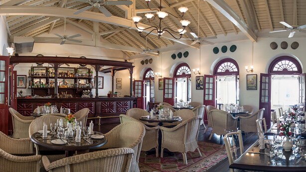 A spacious dining area with high ceilings, chandeliers, and wicker furniture. - Royal Bar & Hotel (Kandy)
