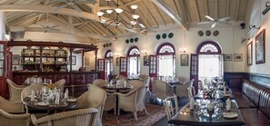 A spacious dining area with high ceilings, chandeliers, and wicker furniture. - Royal Bar & Hotel (Kandy)
