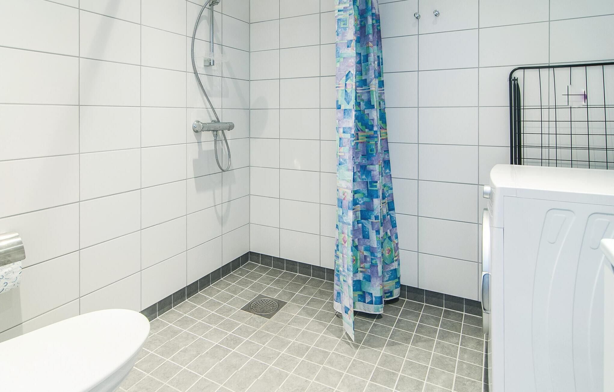 Un bagno piccolo rivestito di piastrelle con doccia, wc e termosifone.