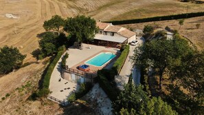 Vista aérea de um imóvel com piscina, área de varanda e um pequeno edifício com telhado de azulejos.