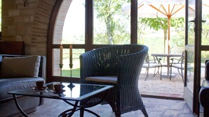 Un espace patio accueillant, doté de meubles en osier, d’une table en verre et offrant une vue sur l’extérieur.