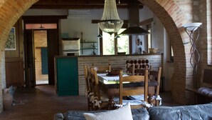 Un salon chaleureux avec un canapé en cuir, une table à manger avec des chaises et une arche en briques.