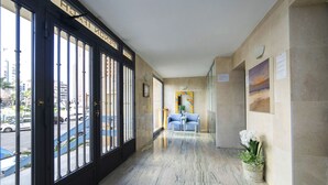 Et hotellobby med et marmorgulv, en receptionsdisk og udsigt til gaden.