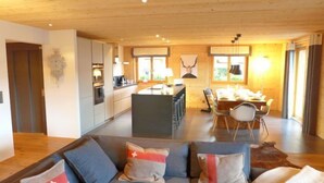 Un salon moderne comprenant un ensemble de canapés, un coin repas et une cuisine.