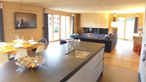 Une cuisine moderne dotée d’un îlot central, de meubles en bois et d’un coin repas avec une table dressée pour quatre personnes.