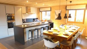 Une cuisine moderne dotée d’un îlot central, de tabourets de bar et d’une table à manger pouvant accueillir six personnes.