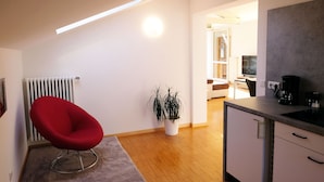 A modern kitchen with a built-in stove, a red chair, and a potted plant. - Refuge with a wonderful view (MERAN)
